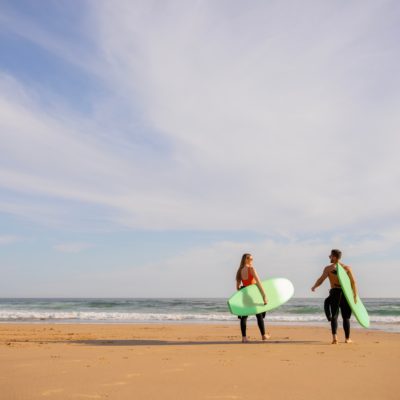 Deux personnes avec des planches de surf qui se dirigent vers l'océan
