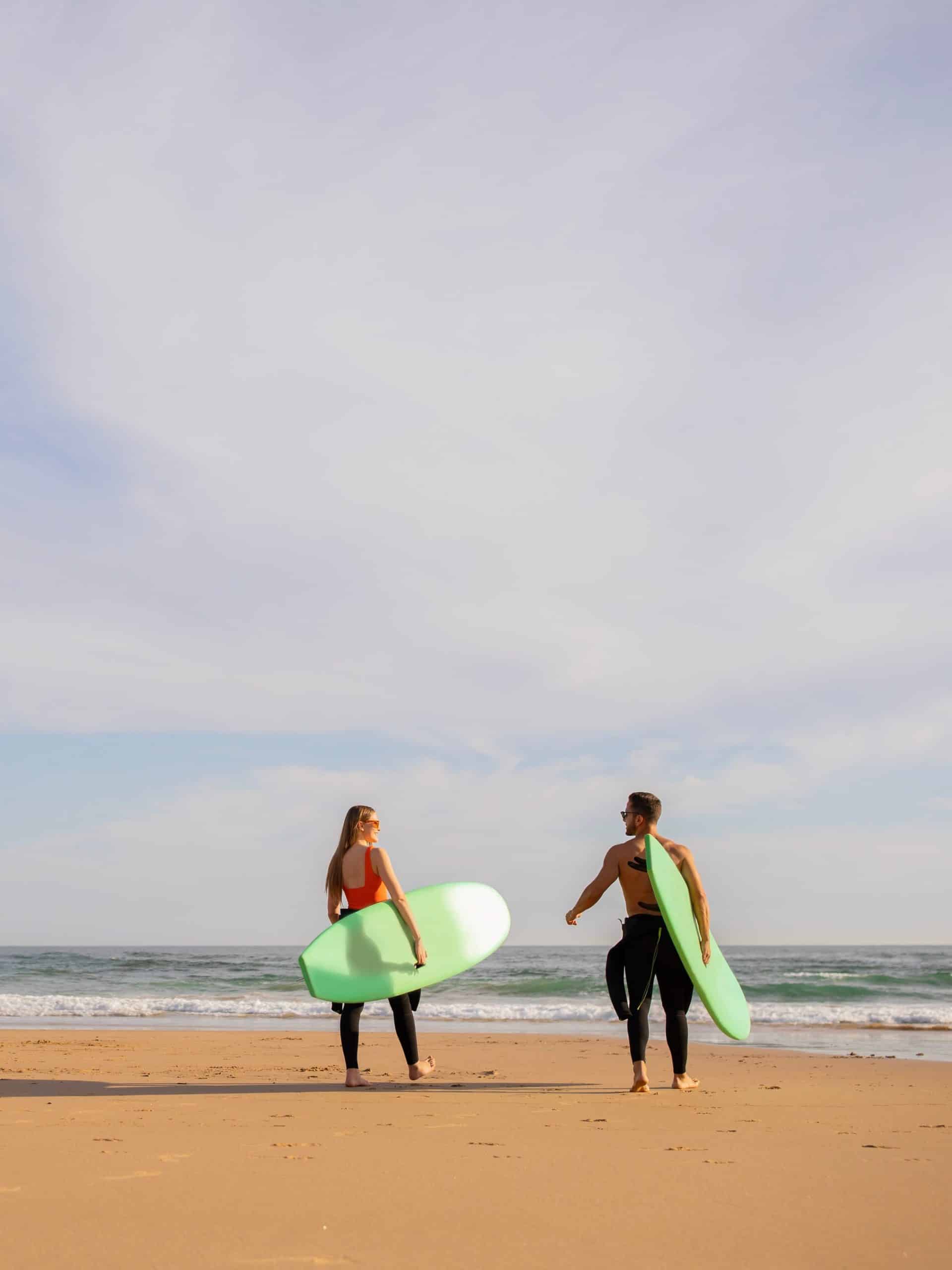 Deux personnes avec des planches de surf qui se dirigent vers l'océan