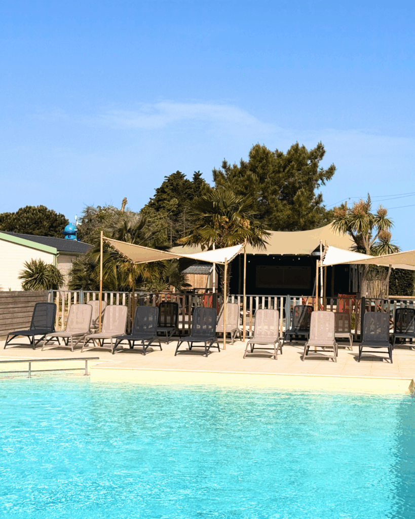 Piscine extérieure avec chaises longues et parasols.